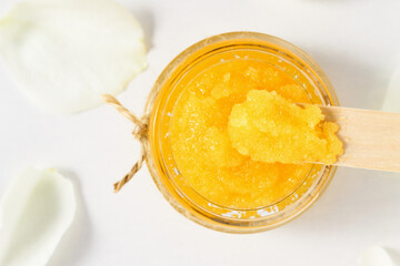 Homemade orange scrub in a glass container top view. Body care, skin cleanser close-up.