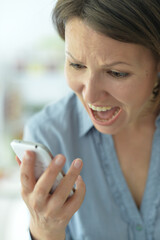 Close-up of a woman screaming at mobile phone