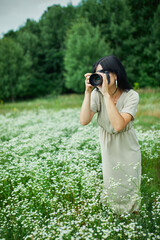 Female photographer take photo outdoors on flower field landscape holding a camera