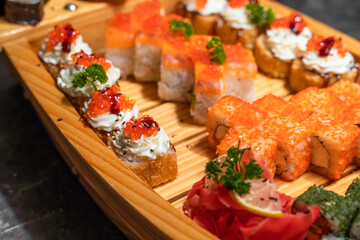 Close-up of japanese rolls with rice and red, black caviar on a wooden tray