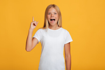 Surprised cheerful caucasian teen girl in white t-shirt with open mouth showing thumb up