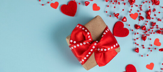 banner with Valentine's Day background. Gift, confetti, beads with hearts on pastel blue colors. Valentine's Day concept. Flat lay. Top view. Copy space