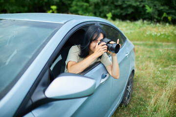 Woman photographer sitting in the car and photographing a flower field landscape