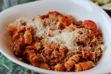A plate of pasta bolognese with fusilli in Zürich, Switzerland. Plate of delicious pasta Italian style. Full of carbohydrates and fat but super yummy! Closeup color image.