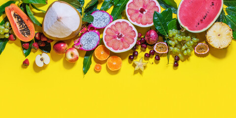 Assortment of exotic tropical fruits and berryes in line on yellow background.
