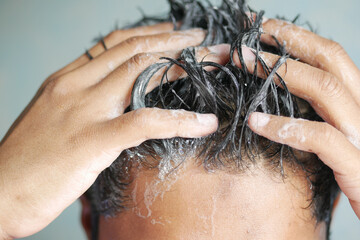 young men washes h his hair with shampoo . - obrazy, fototapety, plakaty