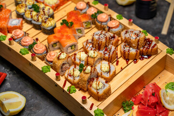 large set of Japanese rolls and sushi on a black background, wooden tray