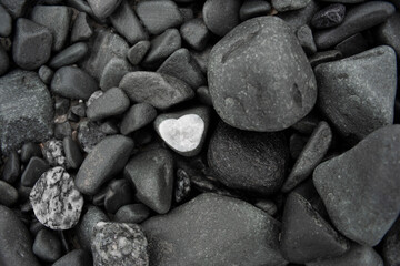 Stone with white heart surrounded by black stones.