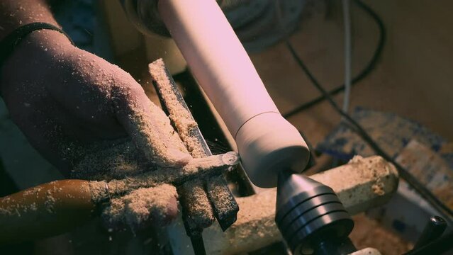 A worker cuts a leg on a lathe with a tool on wood