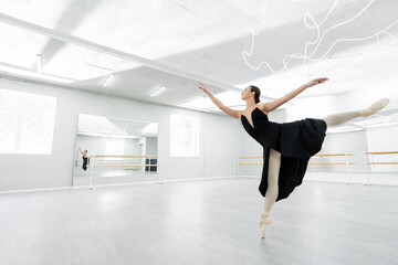 Fototapeta na wymiar full length view of ballerina dancing in spacious studio during repetition