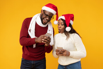 African Man Showing Smartphone To Girlfriend Recommending Application, Yellow Background