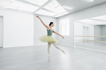 Fototapeta na wymiar full length view of graceful ballerina dancing in spacious ballet studio