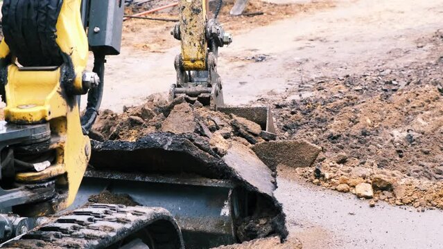 Excavator bucket picks up broken asphalt and earth. Slow motion, 4k