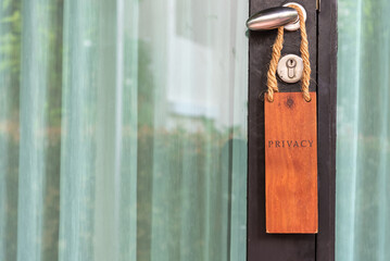 Closed glass door with wooden sign PRIVACY on handle at hotel.