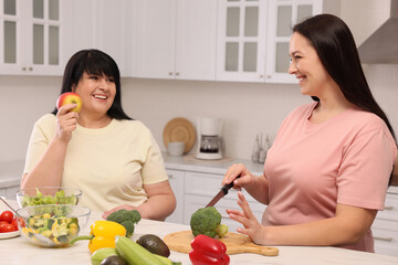 Happy overweight women cooking together in kitchen