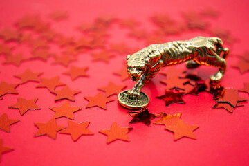 A bronze figure of a tiger with coin - symbol of 2022 year on a red background with stars, copy...