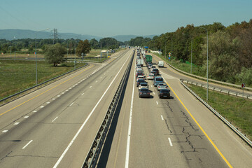 Fototapeta premium One-way traffic jam on the expressway. Traffic jam on the highway. Blue sky and mountains in the background.