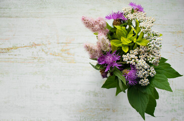 A bouquet of wild flowers on a wooden background. Rustic style. Copy space