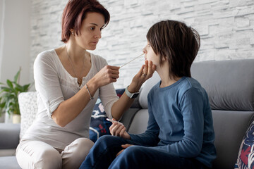 Mother, testing her child for covid 19 at home, making SWAB antigen test, home allowed tests.
