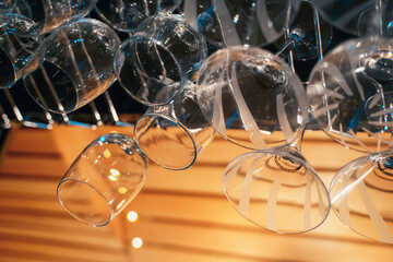 Close-up of inverted transparent wine glasses on a bar in a nightclub