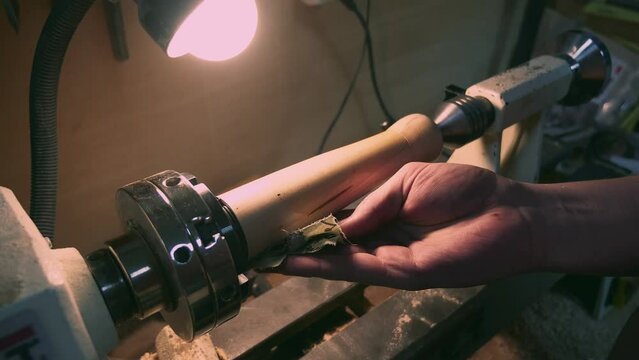 A worker sanding a wooden leg on a lathe
