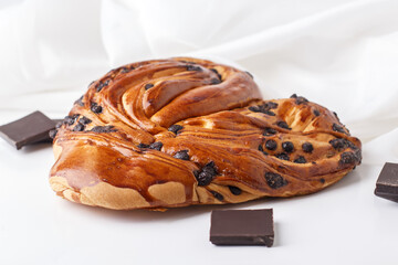 Sweet bun with chocolate pieces on a light background