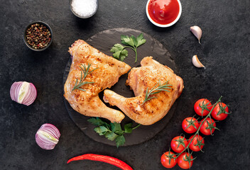 two grilled chicken legs with spices and herbs on a stone background