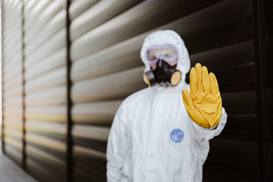 man in a protective suit in front of a building with yellow glowers