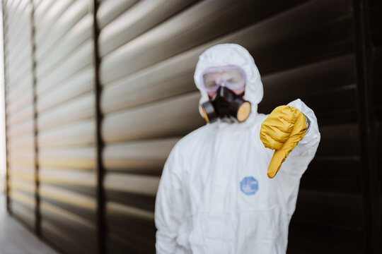 man in a protective suit in front of a building with yellow glowers