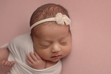 Closeup of sleeping newborn baby girl lying on pink cloth