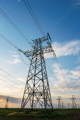 silhouette of high voltage power lines against a colorful sky at sunrise.