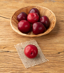 Plums in a basket over wooden table