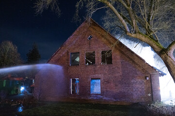 Feuerwehrmann l&ouml;scht Geb&auml;ude mit Kellerbrand