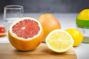 Sliced grapefruit and lemon on wooden board on light table against dark gray background. Citrus water cooking. Selective focus.