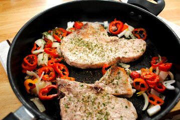 Cooked Pork Chops in a Pan with Onion and Mini Sweet Peppers 