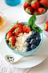 Bowl of cottage cheese with blueberry, strawberry and honey. Soft focus