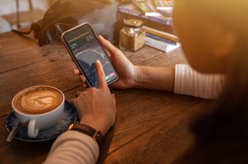 Woman checking cryptocurrency price chart on digital exchange on her smartphone. A cryptocurrency...