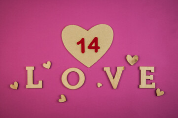 The word Love with small hearts against a pink paper background closeup