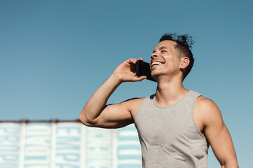 happy young latin caucasian man outside smiling and talking on the phone