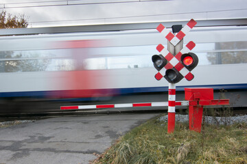 Train passes at crossing with red signal and closed barriers. 