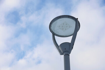 Led lamp with icicles on winter sky background. Electric lighting in park, energy-saving street...