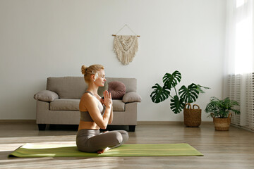 Sporty adult woman practicing yoga in the comfort of her own home. Fit middle aged yogini...