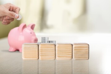 written on wooden blocks with blur of coins and pink piggy bank