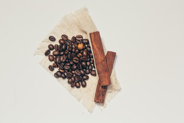 Background, coffee, coffee beans and cinnamon sticks on linen cloth, on white and beige background, isolated