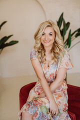 Beautiful happy blonde woman with a sincere smile in a summer dress with a floral print. Soft...