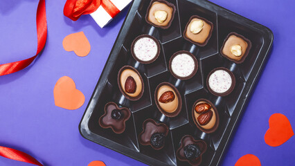 top view of various chocolate pralines in box on violet background.