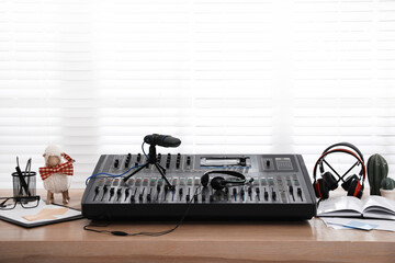 Professional audio equipment and stationery on wooden table in modern radio studio