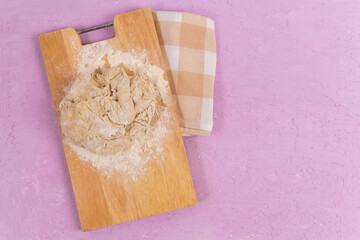 Raw dough purple concrete background, cooking bread, pizza. Copy space. Top view