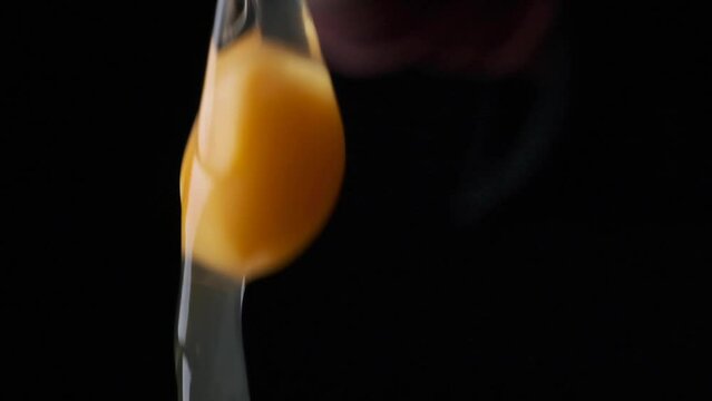 cracking egg egg yolk falling slow motion close up black background
