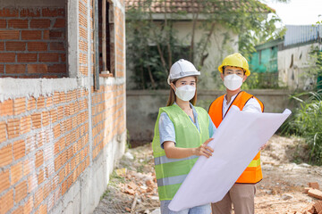 engineer concept The two building directors with a helmet and a mask standing beside the building...